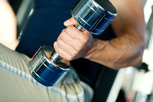 Strong man with dumbbells; focus on hand and dumbbell