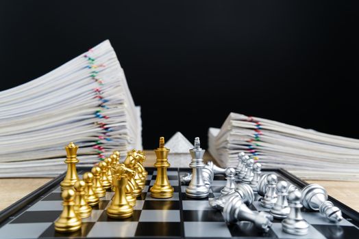 Golden king confront silver king have blur silver chess falling down between overload report of sale and house with black background and copy space. Business and finance concept leader successful.