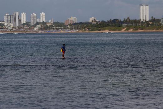 salvador, bahia / brazil - january 24, 2019: fisherman is seen with his fishing rod on Itapua beach in the city of Salvador.