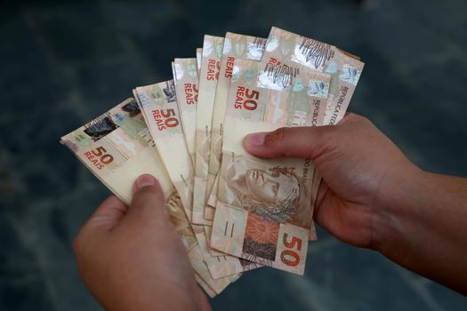 salvador, bahia / brazil - february 25, 2015: Hands hold fifty reais banknotes during counting. R$ 50.

