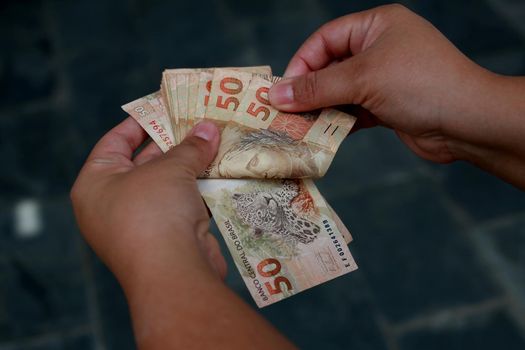 salvador, bahia / brazil - february 25, 2015: hands hold fifty reais (R $ 50.00) bills in the city of Salvador.




