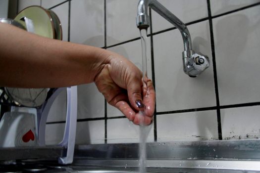 salvador, bahia / brazil - april 26, 2013: person washing hands in kitchen sink in the city of Salvador.




