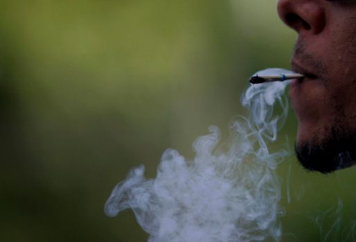 salvador, bahia / brazil - May 26, 2015: Person is seen smoking straw cigarette.



