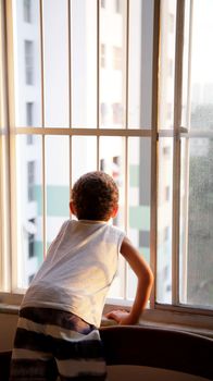 salvador, bahia  brazil - may 27, 2020: child plays next to an apartment window grill during social isolation caused by the corona virus in the city of Salvador.
