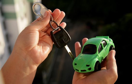 salvador, bahia brazil - may 25, 2020: hand holds replica of a miniature car next to a car key.