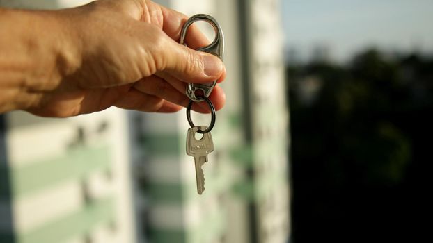 salvador, bahia brazil - may 26, 2020: hand holds apartment key next to a residential building