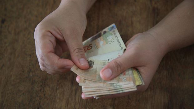 salvador, bahia / brazil - march 28, 2020: woman's hands hold reais banknotes, currency used in Brazil.