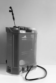 Backpack battery sprayer for protecting trees and plants from diseases and pests. The pressure is increased using a battery-powered pump. Black and white image, copy space