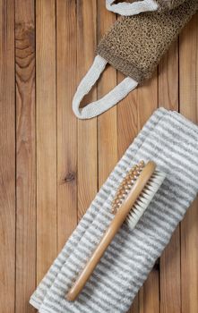 Accessories for visiting the bath or sauna on a wooden background: towel, washcloth, massage brush. Top view with copy space. Flat lay