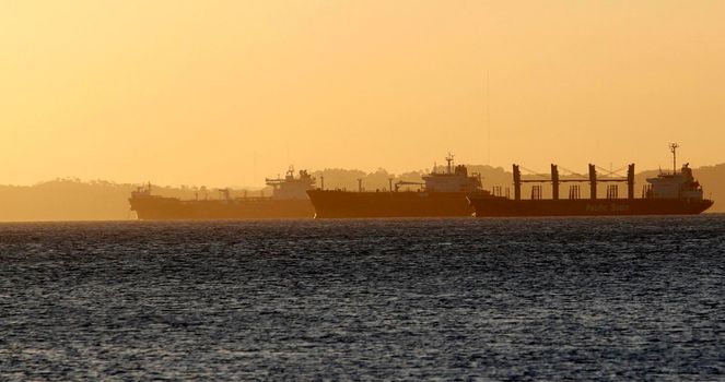 salvador, bahia / brazil - october 1, 2014: cargo ship is seen alongside a sailboat in the waters of Baia de Todos os Santos, in the city of Salvador.