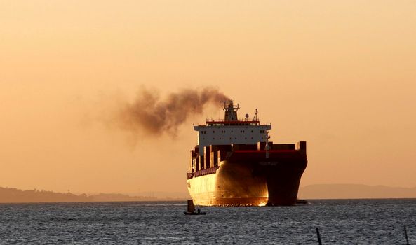 salvador, bahia / brazil - october 1, 2014: cargo ship is seen alongside a sailboat in the waters of Baia de Todos os Santos, in the city of Salvador.