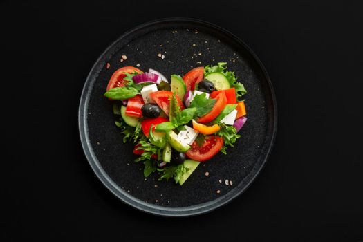 Greek salad in heart shape love food concept, black stone luxury plate, top view flat lay design, black background