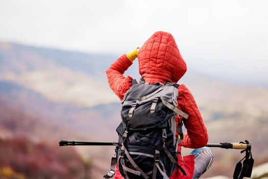 Hiker girl taking a rest on a rock in the mountains. Enjoying the view. Travel and healthy lifestyle outdoors in fall season