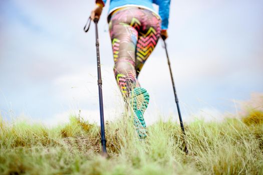 Hiking girl in a mountain meadow. Low angle view of generic sports shoe and legs on grass. Healthy fitness lifestyle outdoors.