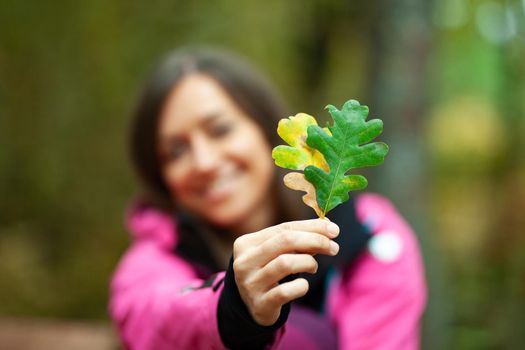 Girl in pink holding two autumn leaves. Fall season in the mountaing. Focus on leaves.