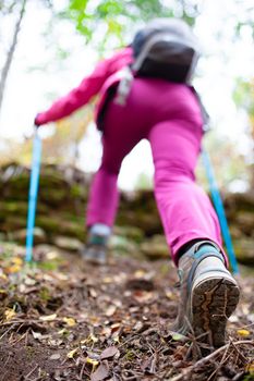 Hiking girl in a mountain. Low angle view of generic sports shoe and legs in a forest. Healthy fitness lifestyle outdoors.