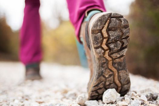 Hiking girl in nature. Low angle view of generic sports shoe and legs on pebble dirt road. Healthy fitness lifestyle outdoors.