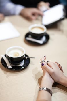 Colleagues having a business meeting at a cafe. Drinking coffee and working on laptop and tablet.