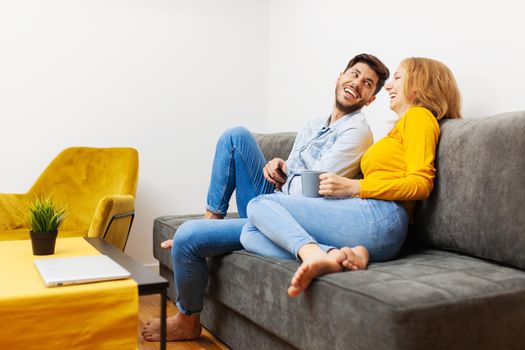 couple in love on a sofa watching tv and smiling