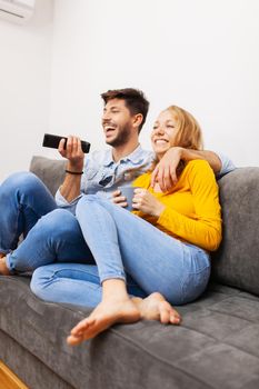 couple in love on a sofa watching tv and smiling