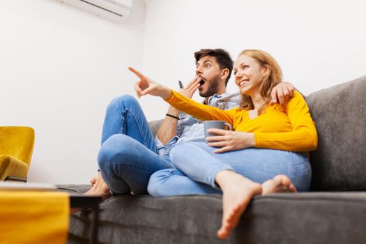 couple in love on a sofa watching tv and smiling