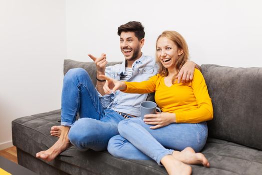 couple in love on a sofa watching tv and smiling
