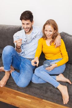 couple in love on a sofa watching tv and smiling