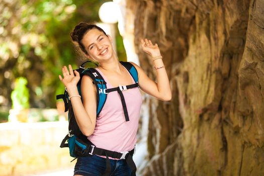 young and happy hiker girl posing next to a rocky passage