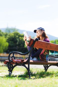 brunette girl with a cap, reading a book sitting on a bench