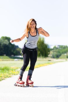 roller skating girl on asphalt road outdoors on a hot summer day