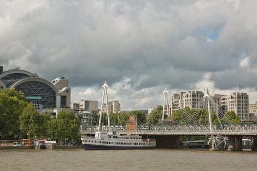 LONDON, UK - SEPTEMBER 08, 2017: View of the Golden Jubilee Bridges and Charing Cross Station from the South Shore of the River Thames in London on a cloudy Summer day.