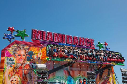 WEYMOUTH, DORSET, ENGLAND, UK - AUGUST 15, 2017: Carousel in amusement park in Weymouth in UK. People enjoying adrenaline and fun. Beautiful weather, bright blue sky