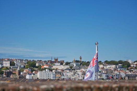 ST. PETER PORT, GUERNSEY, UK - AUGUST 16, 2017: View of a flag and St. Peter Port from Castle Cornet in St Peter Port, Guernsey, UK.