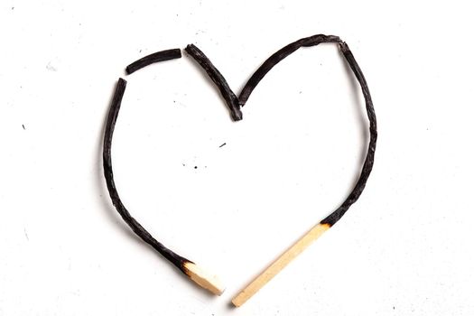 two burned match sticks in a shape of heart