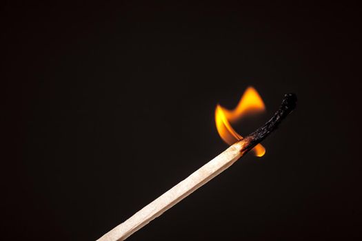one long match stick burning against black background