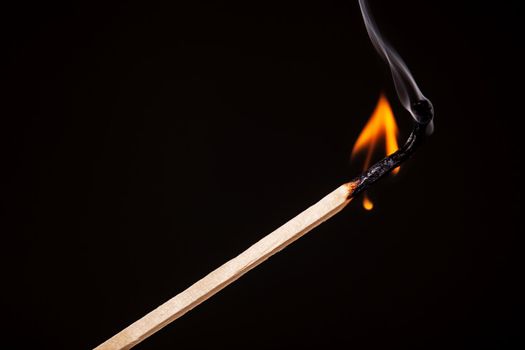one long match stick burning against black background