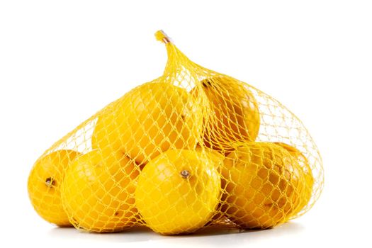 group of ripe lemons in a mesh bag against white background