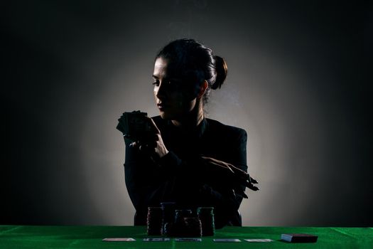 silhouette girl playing poker with lot of chips and holding a cigar