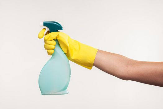hand in yellow glove spraying liquid cleaning detergent in the air