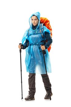 girl with hiking equipment and large backpack, wearing blue raincoat, posing in studio isolated on white.
