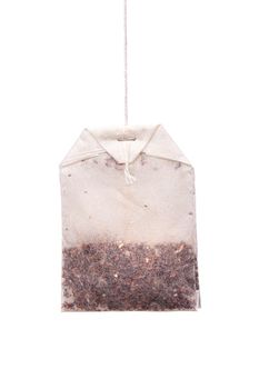 Herbal tea in paper bag. Teabag hanging against white background.