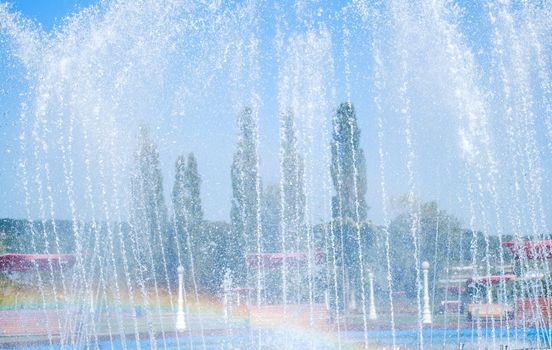 artesian fountain on blue sky with rainbow