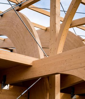 Detail of a modern wooden architecture in glued laminated timber on a blue cloudy sky