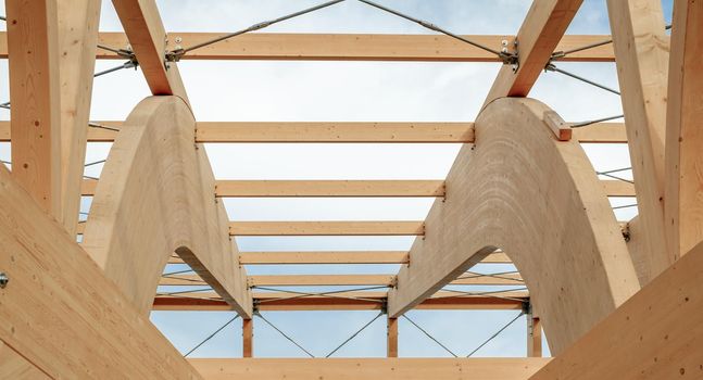 Detail of a modern wooden architecture in glued laminated timber on a blue cloudy sky