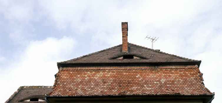 Romanian ceramic shingle roof with brick chimney and old television antenna