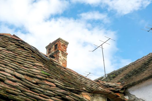 Romanian ceramic shingle roof with brick chimney and old television antenna