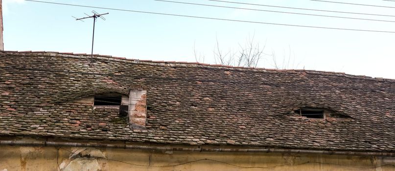 Romanian ceramic shingle roof with brick chimney and old television antenna