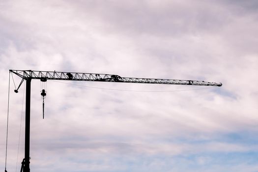 the silhouette of a crane against the cloudy sky