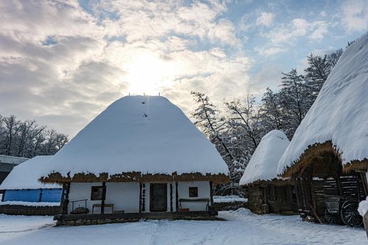 Traditional Romanian village with old house straw roofing covered with snow