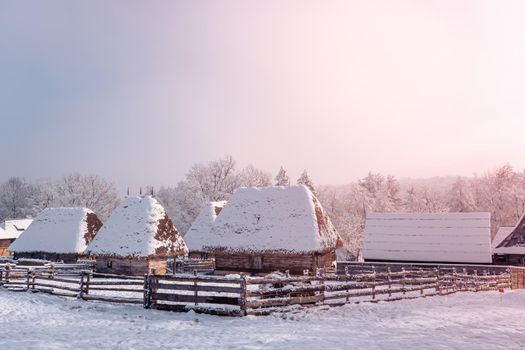 Traditional Romanian village in Transylvania with old house straw roofing covered with snow in a cold day